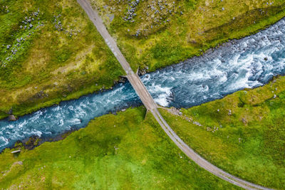 High angle view of stream flowing amidst land