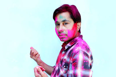 Portrait of senior man holding umbrella against blue background