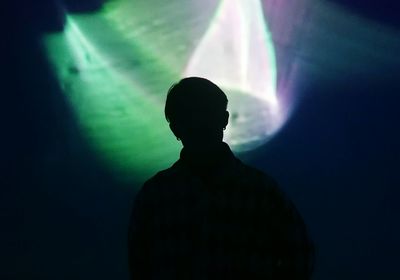 Silhouette of man standing against wall