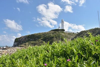 Lighthouse on field by mountain against sky