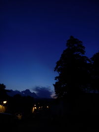 Low angle view of silhouette trees against blue sky