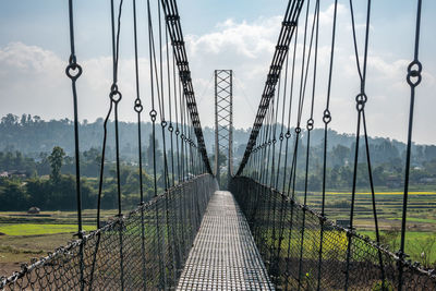 View of suspension bridge against cloudy sky