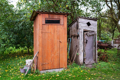 Old and next to it a renovated wooden toilet in the garden outside in the open air.