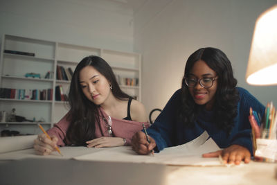 Two young student draws on a paper