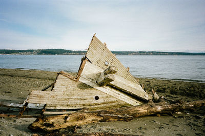 Abandoned boat on beach against sky