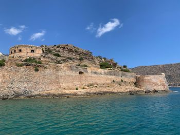 Rock formations by sea against blue sky