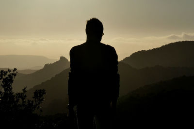 Silhouette man looking at mountains against sky