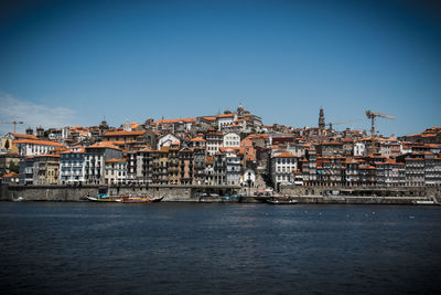 View of town by sea against clear blue sky