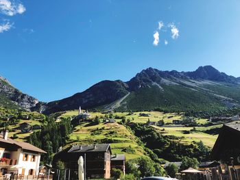 Houses amidst trees and buildings against blue sky