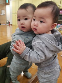 Cute baby boy standing against mirror at home