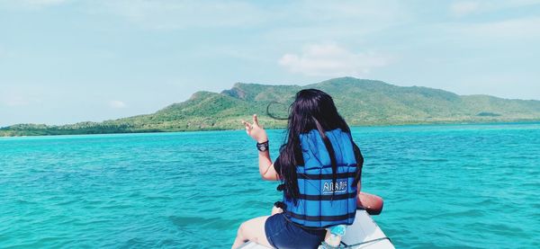 Rear view of woman in sea against sky