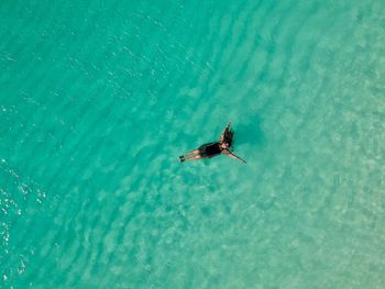 High angle view of woman floating on water with arms outstretched