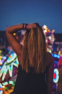 Rear view of young woman standing outdoors at dusk