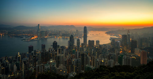 Illuminated cityscape against sky during sunset