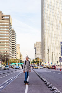 Front view of a young teen with backpack skateboarding in city street