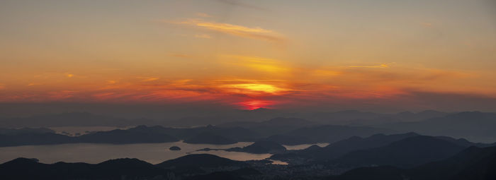 Scenic view of dramatic sky over silhouette landscape during sunset