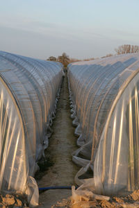 Panoramic shot of greenhouse on field against sky