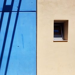 Low angle view of blue window on wall of building