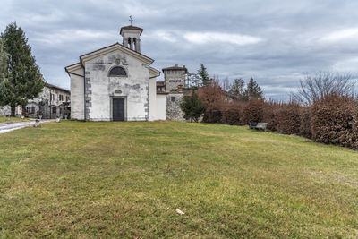 Church on field by building against sky