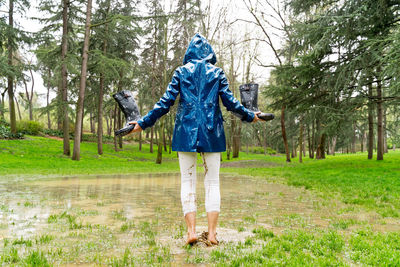 Woman holding rubber boots playing in mud