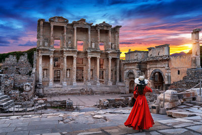 Woman standing in front of historical building against cloudy sky