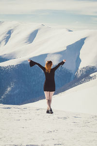 Joyful woman in black dress on snowy ridge scenic photography