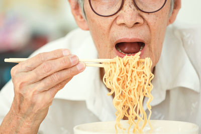 Senior woman eating noodles