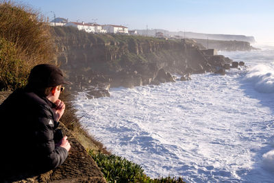 Rear view of man looking at sea against sky