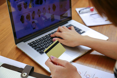 Midsection of woman using mobile phone on table