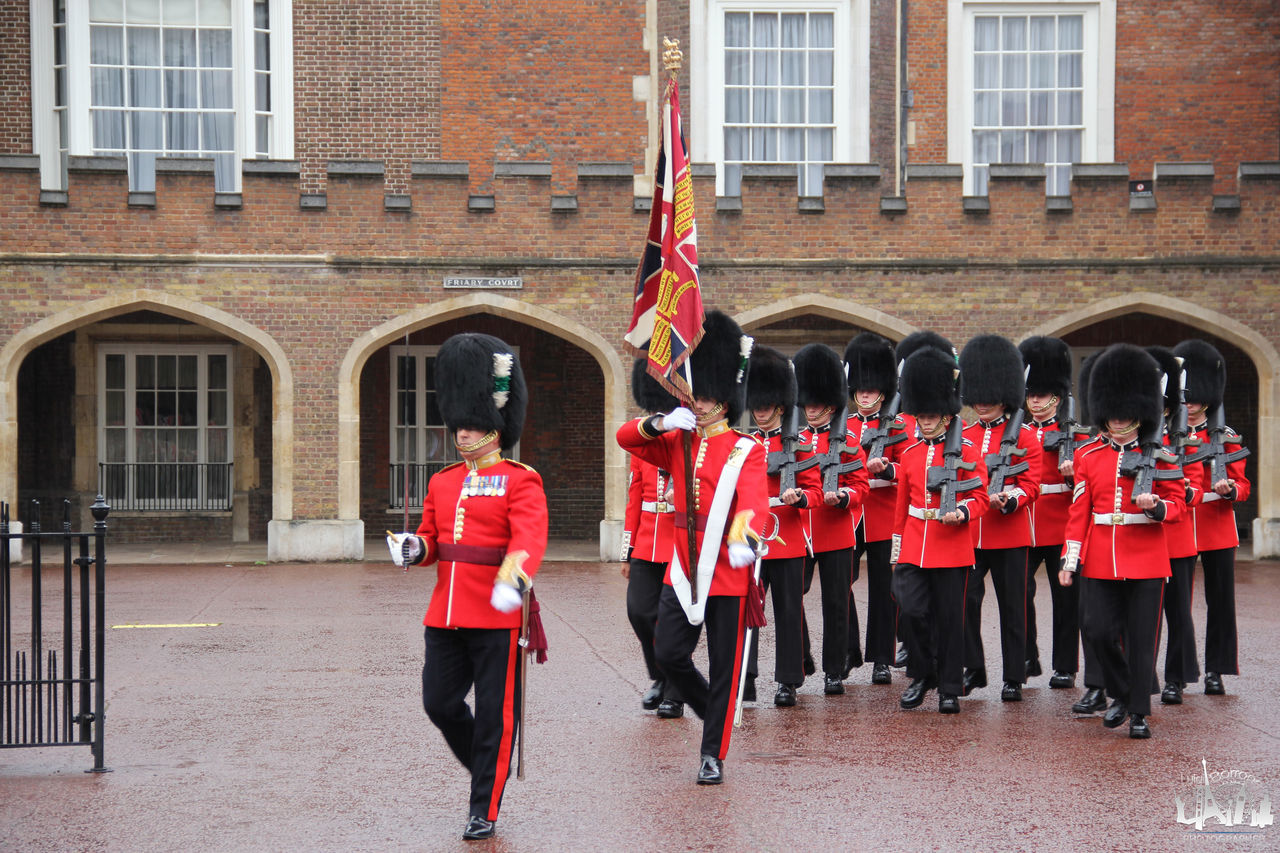 architecture, building exterior, built structure, uniform, group of people, clothing, military uniform, military, red, celebration, government, adult, city, building, full length, men, women, event, marching, day, musician, person, togetherness, armed forces, outdoors, crowd, pride