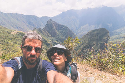 High angle portrait of mature couple hiking on mountain during sunny day