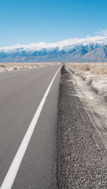 Empty road by mountains against sky