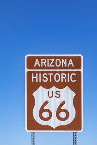 Close-up of road sign against clear blue sky