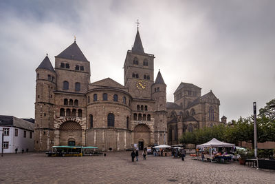 People in front of historic building against sky in city