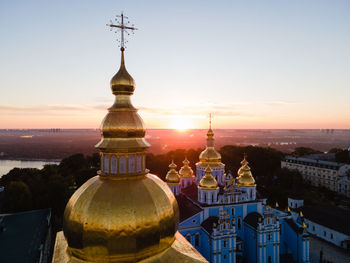 Cathedral against buildings in city at sunset