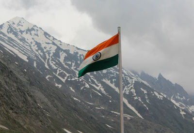 Flag on snowcapped mountains against sky