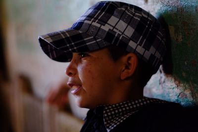 Close-up side view of boy wearing cap by wall