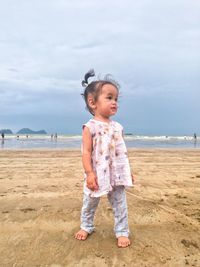 Boy standing on beach against sky