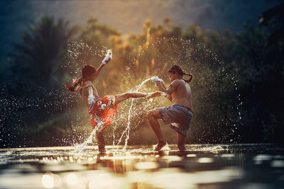 Side view of boys fighting in water