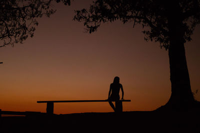 Silhouette men standing against orange sky