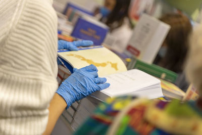 Midsection of woman holding book wearing gloves