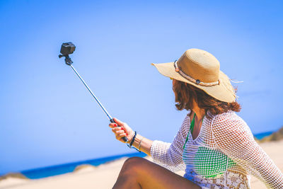 Midsection of woman holding smart phone against clear sky