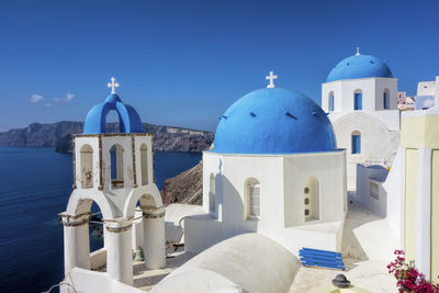 Church by sea against blue sky on sunny day