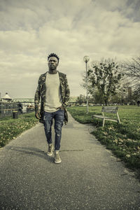 Full length portrait of young man standing against sky