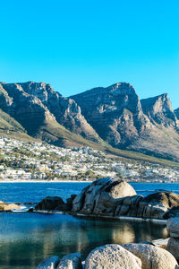 Scenic view of lake and mountains against clear blue sky