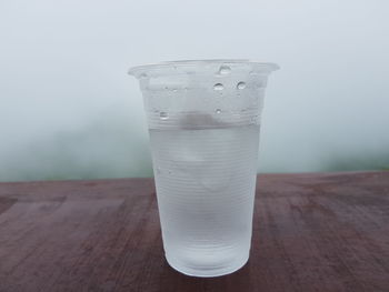 Close-up of drink on wooden table during foggy weather