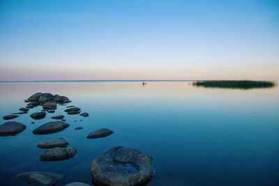 Stepping stones in sea against clear sky