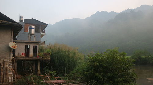 House amidst trees and buildings against sky