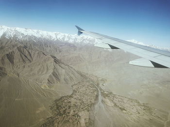 Airplane flying over landscape against sky