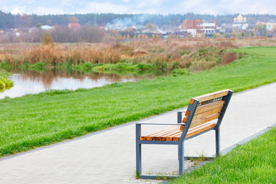 Wooden bench with a metal frame on a walking path paved with paving stones, among a green lawn